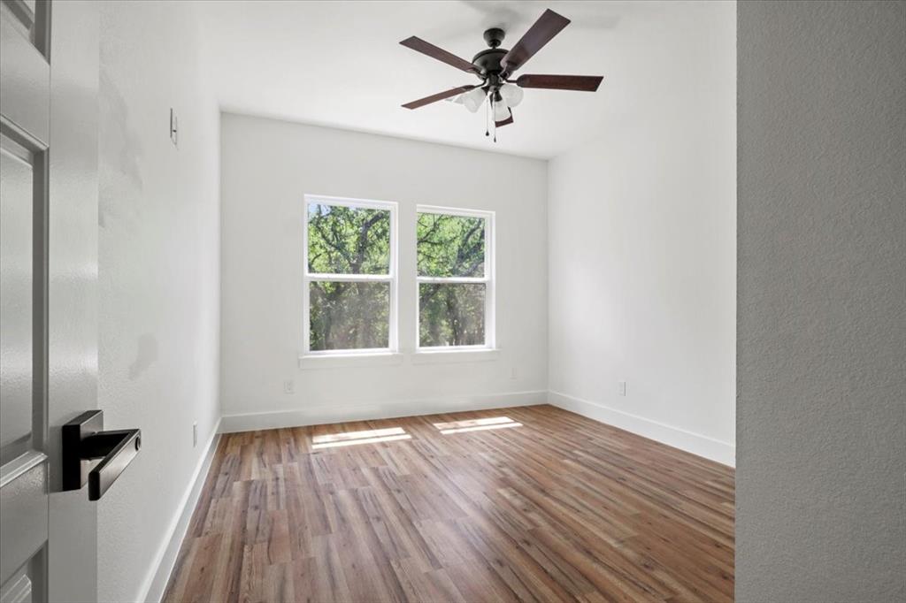 1791 JE Woody Road Springtown, TX 76082 - Photo 29 of 33 an empty room with wooden floor a ceiling fan and windows