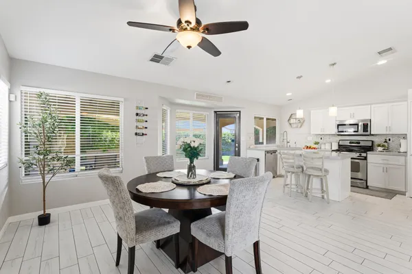 a view of a patio with table and chairs potted plants with floor to ceiling window