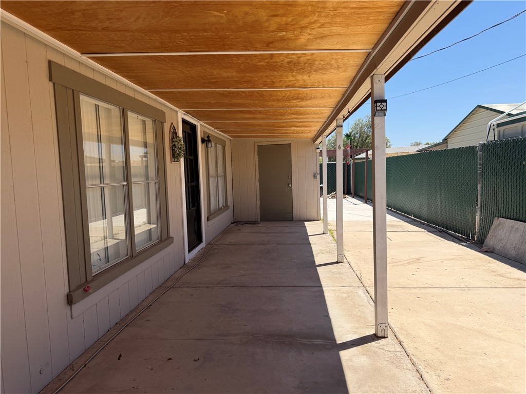1910 Rio Grande Road Bullhead City, AZ 86442 - Photo 25 of 29 Covered concrete patio with a wood-finish ceiling, flanked by a secure side yard with chain-link fencing