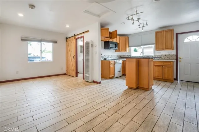 a view of kitchen with stainless steel appliances granite countertop a refrigerator and microwave