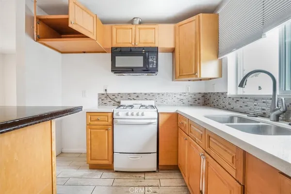 a kitchen with stainless steel appliances granite countertop a sink and a stove top oven with white countertops