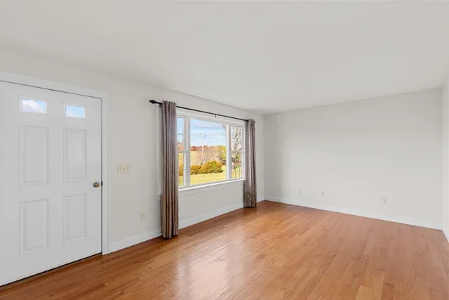 an empty room with a window and wooden floor