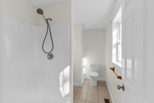 a bathroom with a shower toilet and a window