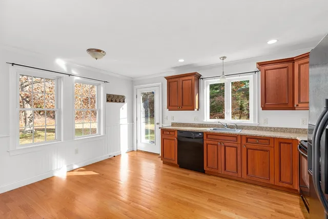 a large kitchen with stainless steel appliances granite countertop a stove a sink dishwasher a refrigerator with wooden cabinets and wooden floor