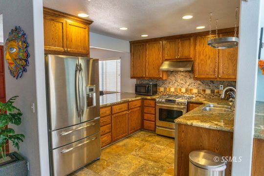 718 La Paloma Street Ridgecrest, CA 93555 - Photo 15 of 50 a kitchen with stainless steel appliances granite countertop a refrigerator a stove and a sink