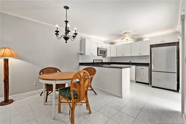 a kitchen with stainless steel appliances kitchen island granite countertop a dining table chairs and a refrigerator
