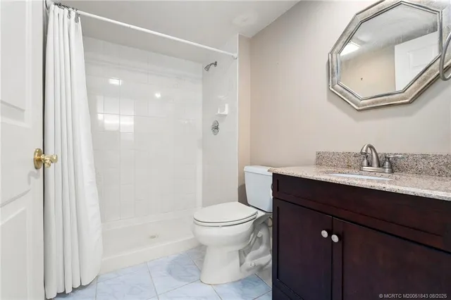 a bathroom with a granite countertop sink toilet and shower