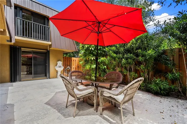 a patio with tables and chairs under an umbrella