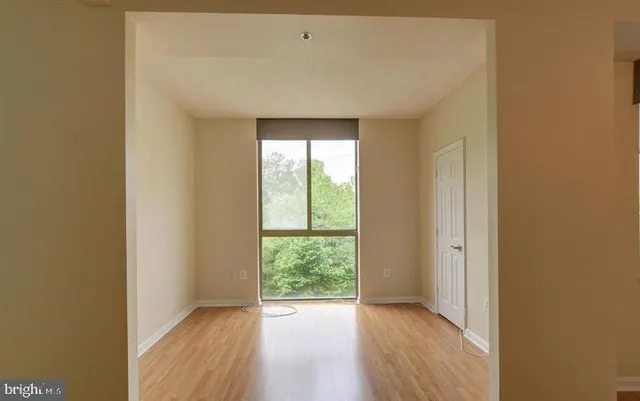 a view of an empty room with wooden floor and a window