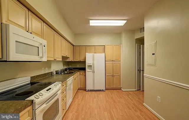 a kitchen with a refrigerator a stove top oven and cabinets