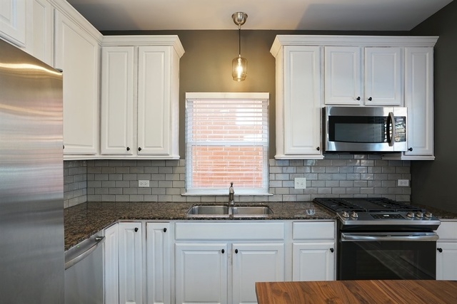 4152 South Berkeley Avenue Chicago, IL 60653 - Photo 6 of 15 a kitchen with granite countertop white cabinets and black stainless steel appliances