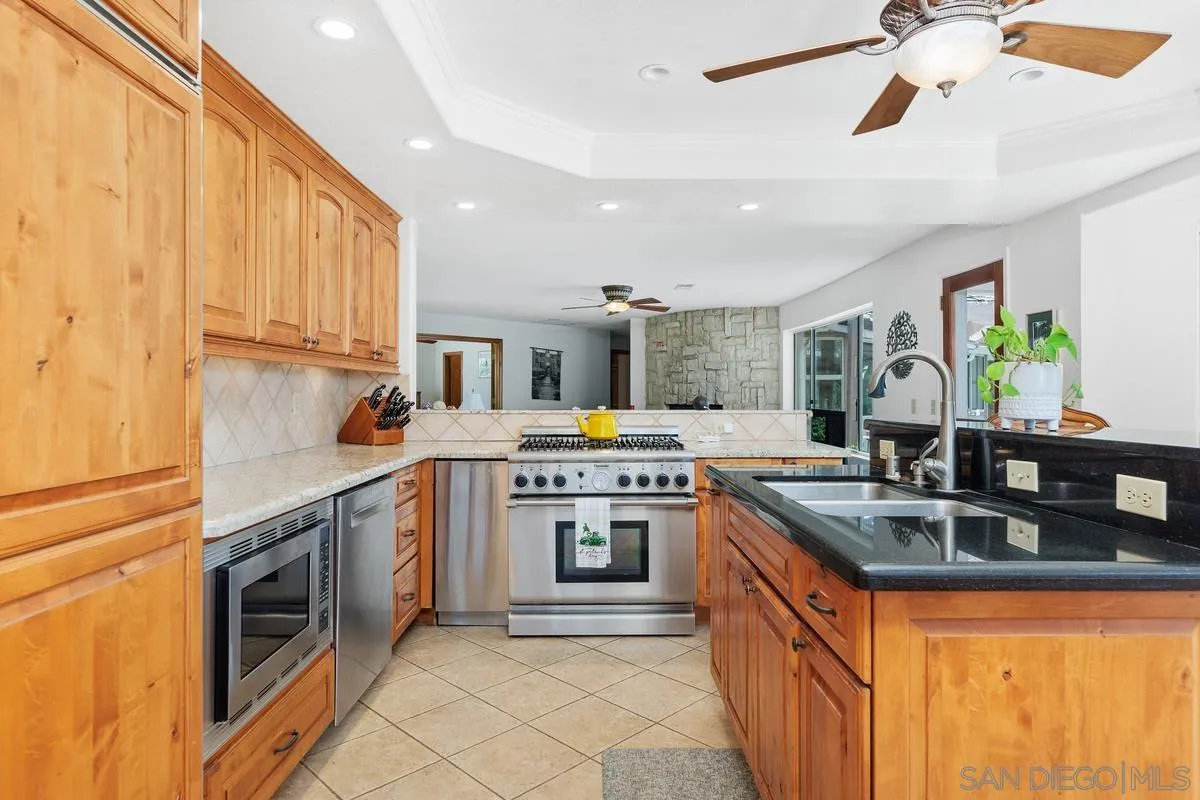 15121 Country Hill Road Poway, CA 92064 - Photo 10 of 40 a kitchen with stainless steel appliances granite countertop a sink and stove top oven