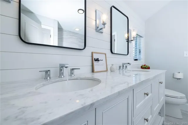 a bathroom with double vanity sink a mirror and a toilet