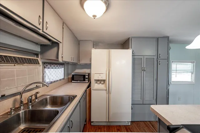 a kitchen with stainless steel appliances a sink a stove a refrigerator cabinets and a dining table