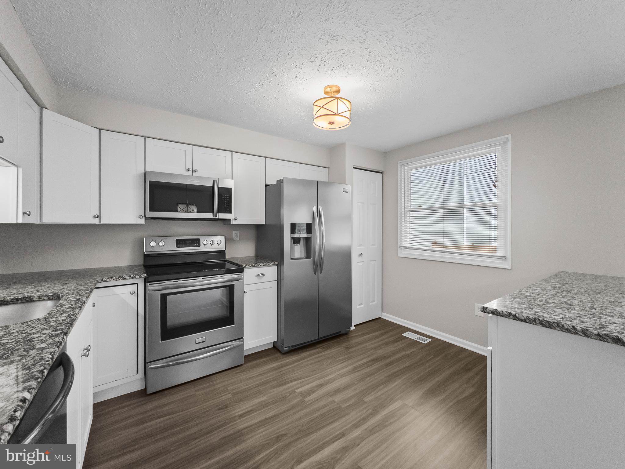 10110 Shelldrake Circle Damascus, MD 20872 - Photo 10 of 35 a kitchen with granite countertop a refrigerator stove and microwave