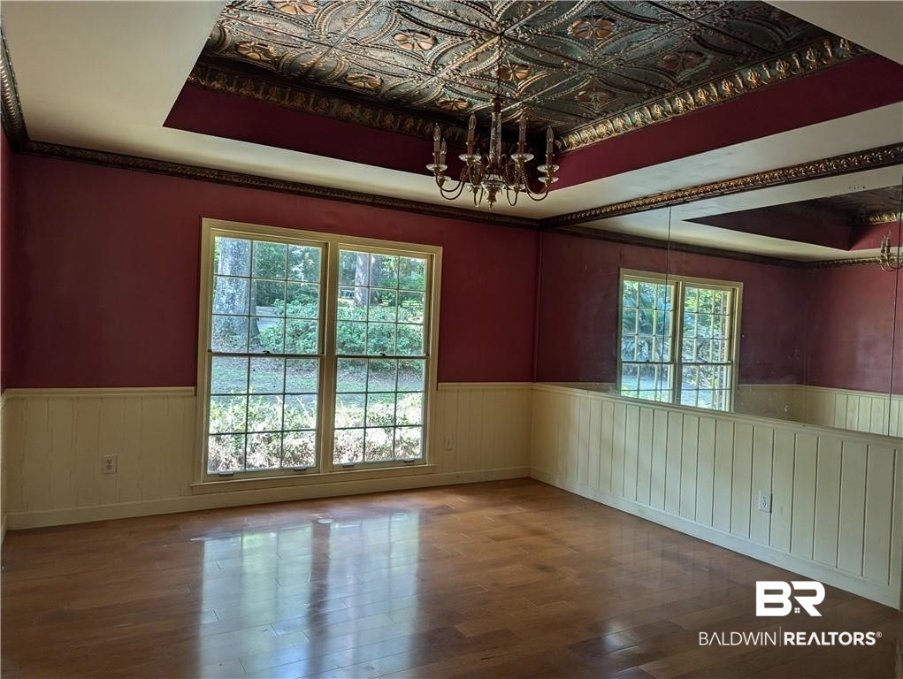3608 Linden Lane Mobile, AL 36608 - Photo 12 of 20 Unfurnished room featuring hardwood / wood-style flooring, a raised ceiling, and an inviting chandelier