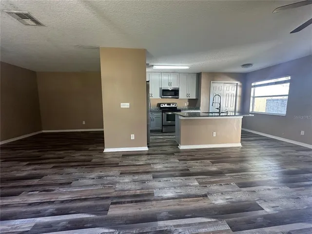 a view of kitchen and empty room with wooden floor