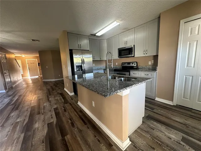 a kitchen with granite countertop a sink a counter top space stainless steel appliances and cabinets