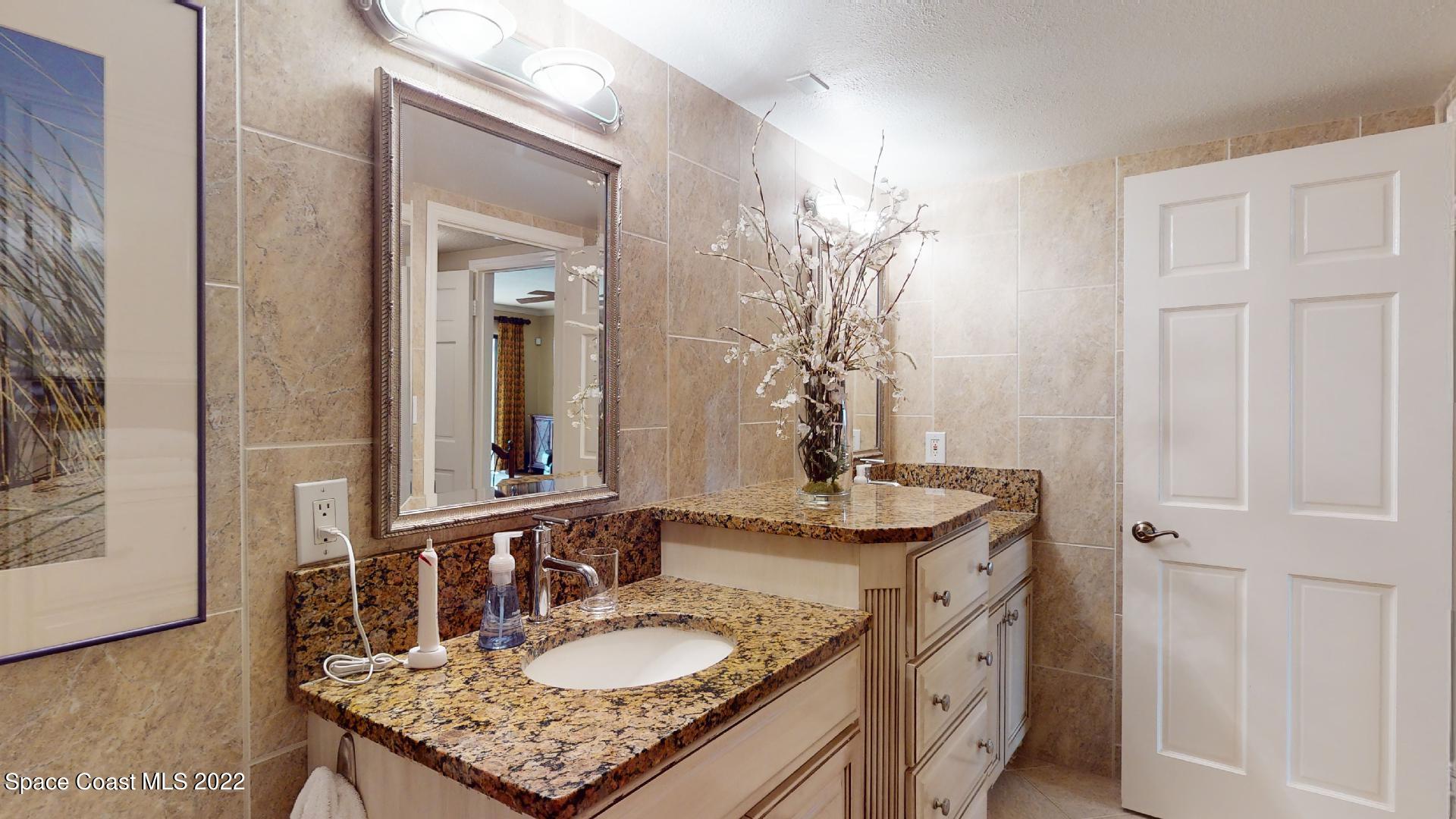 2220 Front Street, Unit 303 Melbourne, FL 32901 - Photo 20 of 29 a bathroom with a granite countertop sink and a mirror