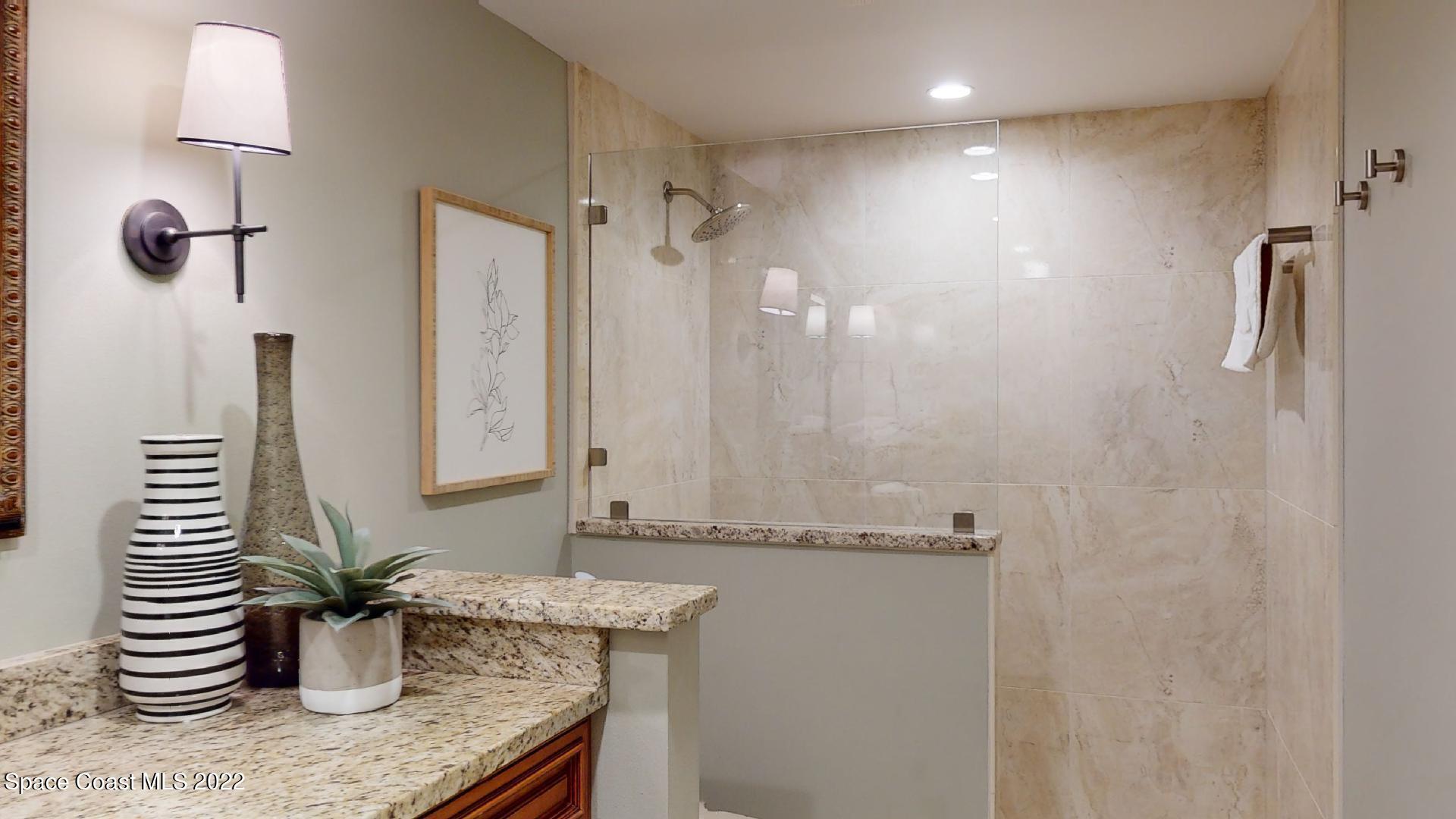 2220 Front Street, Unit 303 Melbourne, FL 32901 - Photo 26 of 29 a bathroom with a granite countertop sink a mirror and a shower