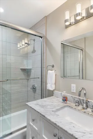 a bathroom with a granite countertop sink a mirror and shower
