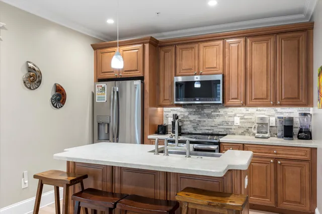 a kitchen with stainless steel appliances wooden cabinets a stove a sink and a microwave