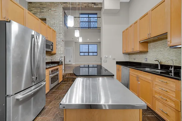 a large kitchen with stainless steel appliances granite countertop a refrigerator a oven and white cabinets with wooden floor
