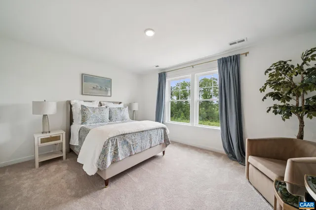 a spacious bedroom with a bed lamp and a large window
