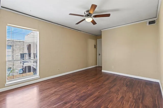 a view of empty room with wooden floor and fan