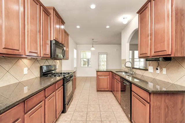 a kitchen with stainless steel appliances granite countertop wooden cabinets a sink and a stove