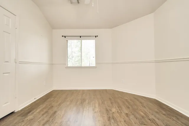an empty room with wooden floor and windows