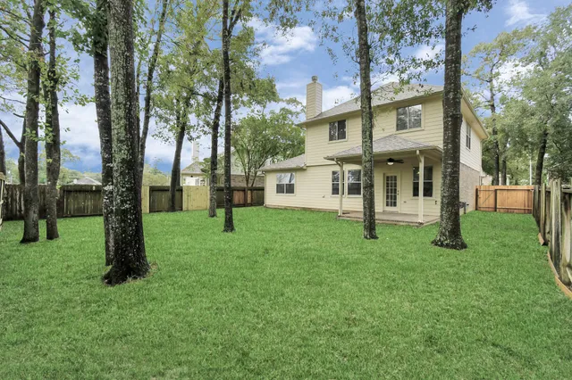 a view of a white house with a big yard and large trees