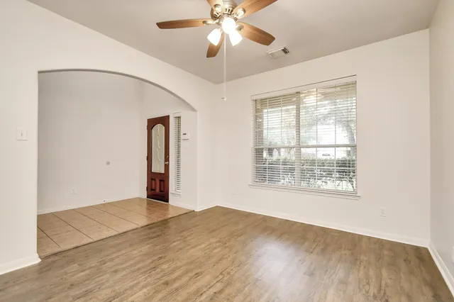 a view of an empty room with wooden floor and a window