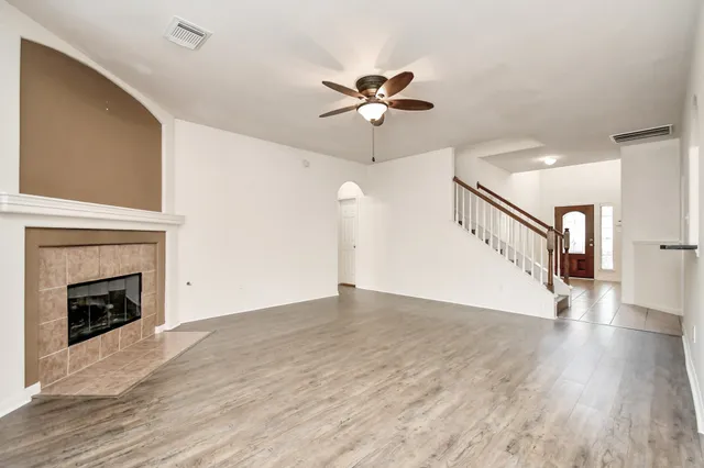 a view of empty room with wooden floor fireplace and fan