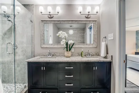 a bathroom with a granite countertop sink a mirror and shower