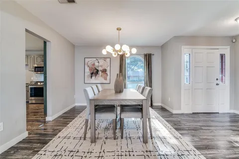 a dining room with wooden floor a chandelier a wooden table and chairs