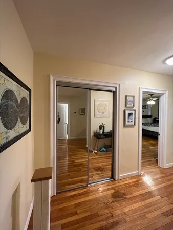 a view of a hallway with wooden floor and dining room