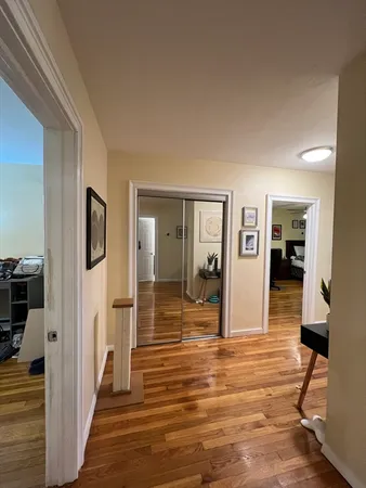 a view of a hallway with wooden floor and livingroom