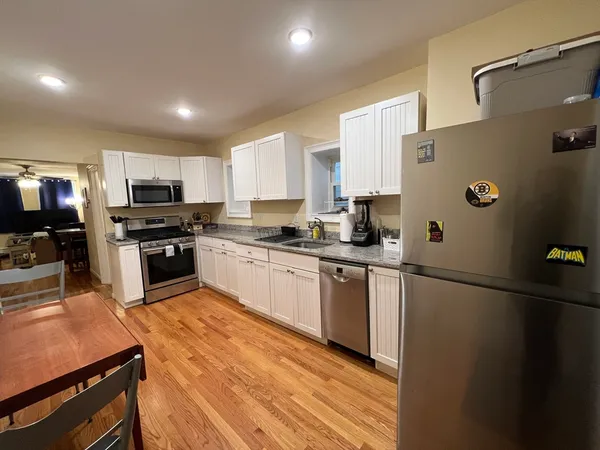 a kitchen with granite countertop a refrigerator a sink a stove top oven and cabinetry