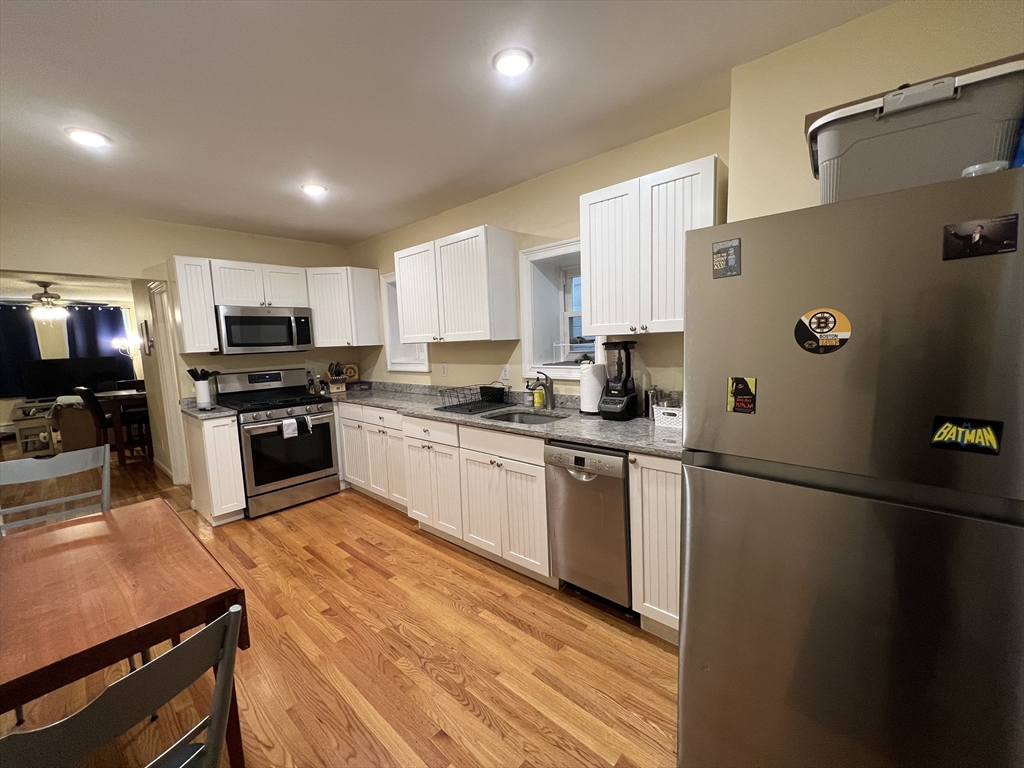 41 Cross Street Somerville, MA 02145 - Photo 34 of 42 a kitchen with granite countertop a refrigerator a sink a stove top oven and cabinetry