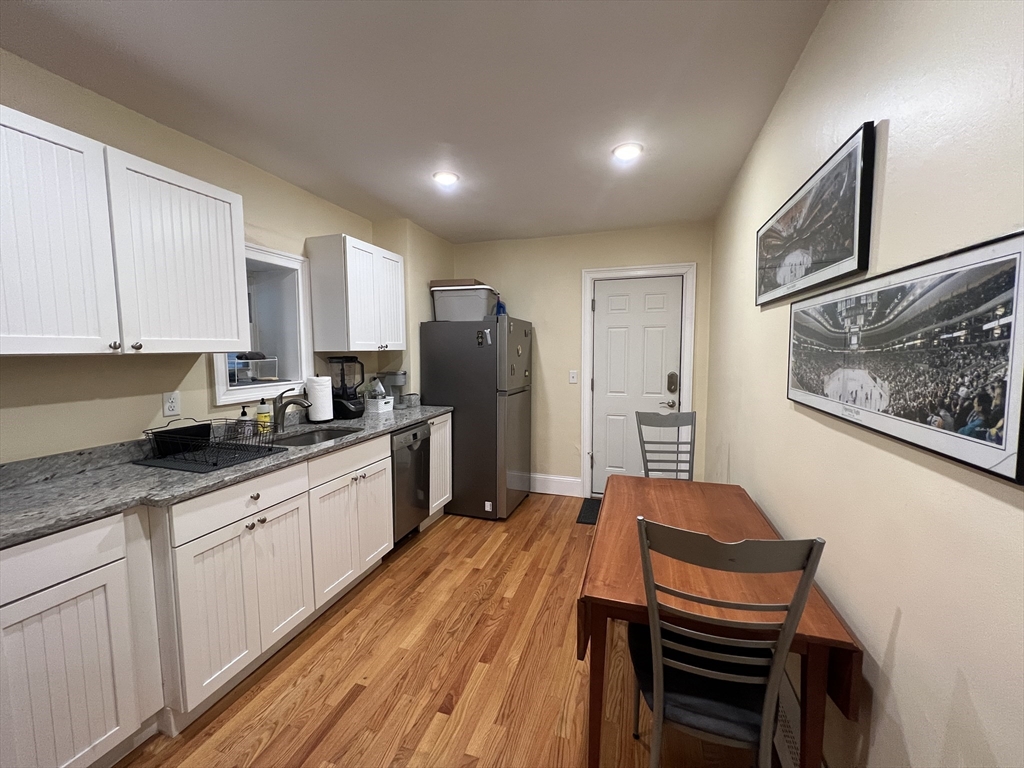 41 Cross Street Somerville, MA 02145 - Photo 40 of 42 a kitchen with stainless steel appliances granite countertop a refrigerator a sink dishwasher a stove and white countertops with wooden floor