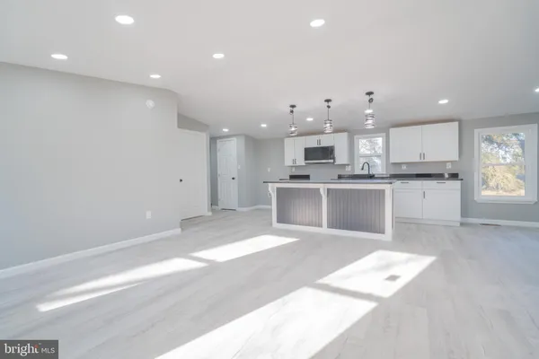 a large white kitchen with kitchen island a sink stainless steel appliances and cabinets