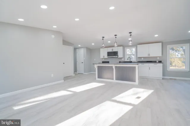 a large white kitchen with kitchen island a sink stainless steel appliances and cabinets