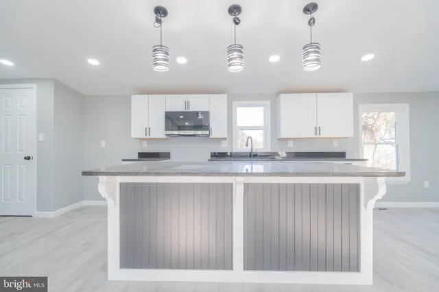 a kitchen with kitchen island granite countertop a sink cabinets and window