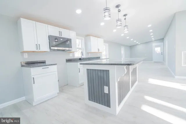 a kitchen with kitchen island white cabinets and stainless steel appliances