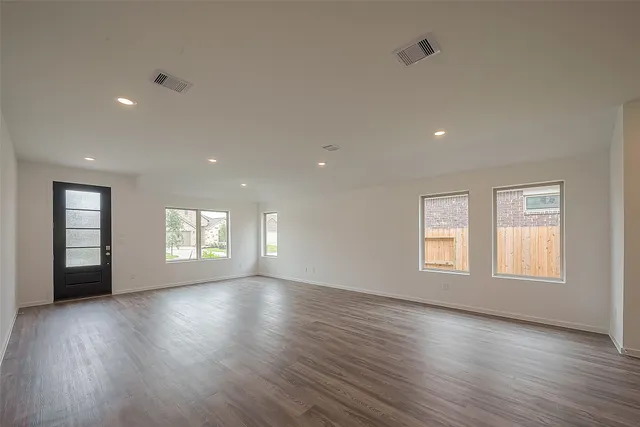 a view of an empty room with wooden floor and window