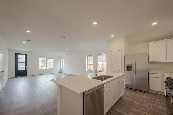 a large kitchen with a large counter top a sink stainless steel appliances and cabinets