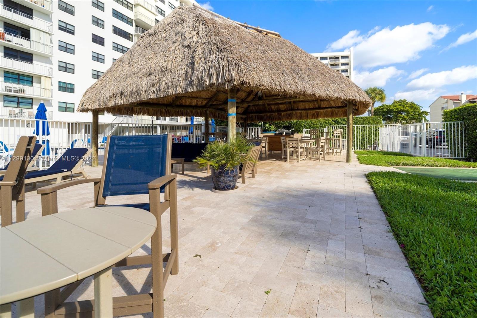 336 Golfview Road, Unit 502 North Palm Beach, FL 33408 - Photo 7 of 7 a view of a patio with a table and chairs under an umbrella with a barbeque