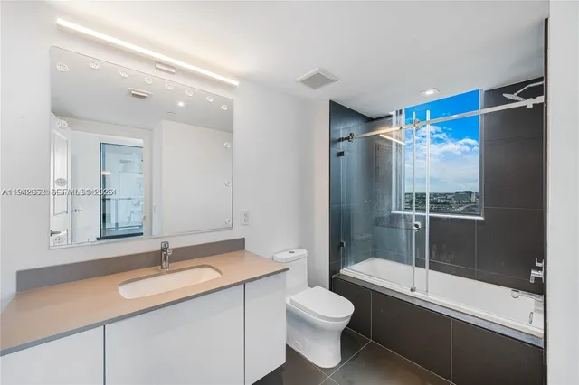 a bathroom with a granite countertop sink toilet and shower