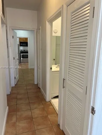a view of a hallway with wooden floor and a bathroom